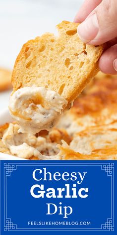 a hand holding a piece of garlic dip over a white bowl filled with cheese and bread