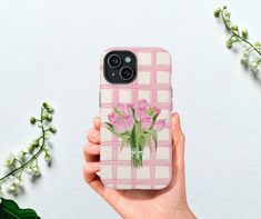 a hand holding a phone case with pink flowers on the front and white checkered background