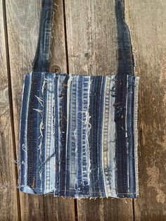 an old denim bag with holes in it on a wooden surface, hanging from a hook