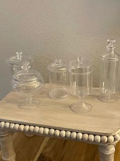 an old table with glass jars and dishes on it