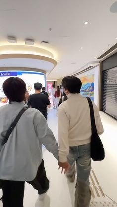 several people walking through an airport terminal holding hands