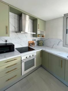 a kitchen with green cabinets and white counter tops, including a stove top oven and microwave