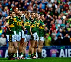 a group of men standing next to each other in front of a crowd on a field