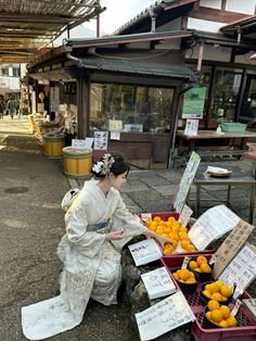 a woman sitting on the ground next to baskets filled with oranges