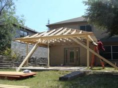 a man standing on top of a wooden deck in front of a house under construction