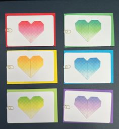 four heart shaped paper clips are shown on a piece of white paper with different colors