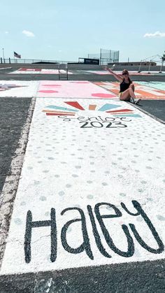 a person sitting on the ground in front of a sign that says hally painted on it