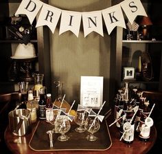 there is a table with wine glasses and liquor bottles on it, along with a sign that says drinks