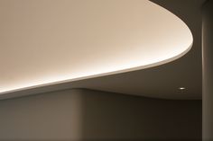 the interior of a modern building with curved ceiling and white walls, along with an oval light fixture