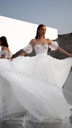 a woman in a white dress standing on the beach