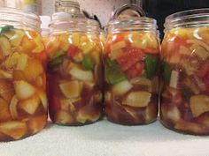 four jars filled with pickled vegetables sitting on top of a counter