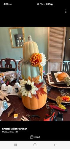 a table topped with lots of fake flowers next to pumpkins and other items on top of it