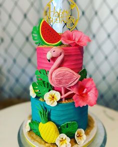 a colorful cake decorated with pink flamingos, watermelon and pineapples