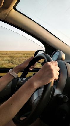 a person driving a car with their hand on the steering wheel