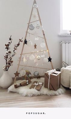 a white christmas tree with ornaments and presents on the floor in front of it, next to a radiator