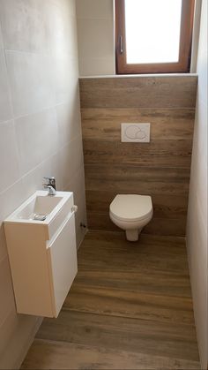 a white toilet sitting in a bathroom next to a sink under a window with a skylight