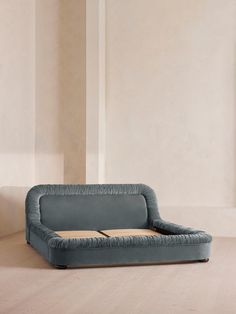 a blue couch sitting on top of a hard wood floor next to a white wall