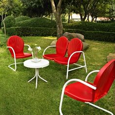 four red chairs and a white table in the grass