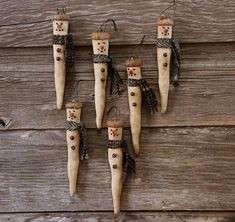 four wooden peg dolls are hanging on a wood wall, with feathers and beads around them