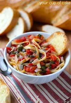 a white bowl filled with pasta and vegetables on top of a red and white towel