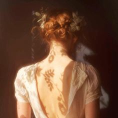 the back of a woman's dress with flowers in her hair, and shadows on it