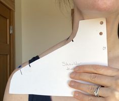 a woman holding up a piece of paper with the word shoulder cut off on it