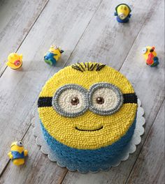 a yellow and blue cake sitting on top of a wooden table next to minion figurines