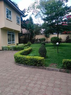 a house with a garden in front of it and some bushes around the yard area