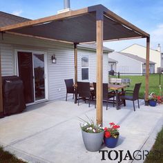 an outdoor patio with potted plants on the ground and a grill in the background