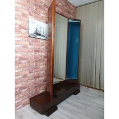 a large mirror sitting on top of a wooden stand in front of a brick wall