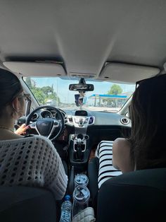 two women sitting in the driver's seat of a car