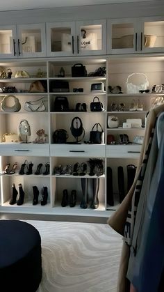 a closet filled with lots of shoes and purses next to a footstool