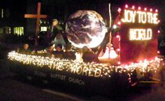 people are riding in the back of a float decorated with christmas lights and an earth globe