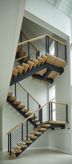 an open staircase with wooden handrails and metal railings in a white room