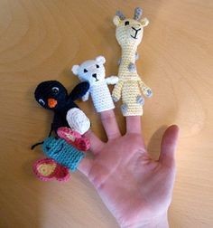 a hand is holding four small crocheted finger puppets on it's palm