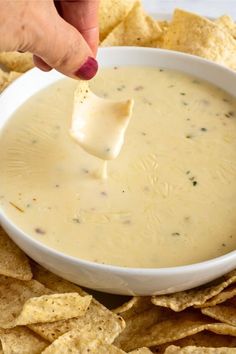 a tortilla chip being dipped into a bowl of quesadilla dip