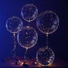 four clear bubbles floating in the air on a table with blue lights and decorations around them