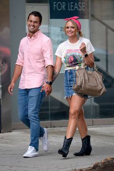 a man and woman are walking down the street holding hands, both wearing cowboy boots