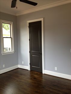 an empty room with hard wood floors and gray walls