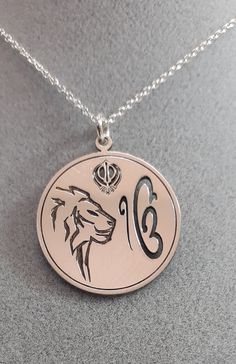 Are you looking for a special gift? How about this precious sterling silver pendant representing the Ik Onkar symbol, the Khanda sword, and the Lion? The Ik Onkar Symbol is the declaration of unity in Sikhism, that is 'there is only one God'. Ik Onkar are the first words of the Mul Mantar and also the opening words of the sacred Sikh scripture Guru Granth Sahib. The double-edged Khanda sword is a metaphor for Divine Knowledge, its sharp edges can separate truth from falsehood. Outside the circle Traditional Round Jewelry For Commemoration, Symbolic Hallmarked Medallion Jewelry, Symbolic Medallion Necklace For Commemoration, Traditional Pendant Jewelry For Commemoration, Symbolic Coin-shaped Jewelry With Large Pendant, Symbolic Jewelry With Large Coin Pendant, Symbolic Large Coin Pendant Jewelry, Symbolic Sterling Silver Necklaces For Commemoration, Symbolic Medallion Jewelry For Commemoration