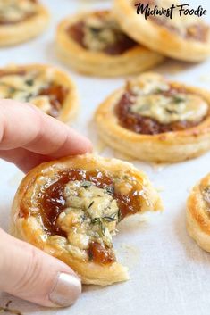 a hand is picking up some puff pastry from the baking sheet with text overlay that says caramelized onion and blue cheese puff pastry