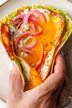 a person is holding up a tortilla filled with meat and veggies