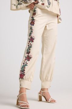 Ivory pant featuring multi color thread and beadwork. - Aza Fashions Bohemian Embroidered Beige Bottoms, Beige Bohemian Embroidered Bottoms, Embellished Spring Trousers, Embellished Spring Bottoms, Beige Floral Embroidery Pants For Summer, Cream Floral Embroidery Bottoms For Summer, Summer Cream Bottoms With Floral Embroidery, Summer Floral Embroidery Cream Bottoms, Cream Bohemian Pants For Spring