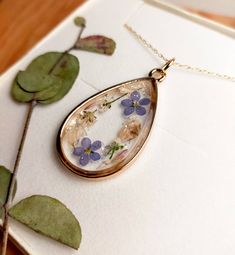 "A beautiful and unique Botanical inspired terrarium necklace with real forget me not flowers and baby breath flowers (gypsophila)  For memories of a close one, for true love and to show someone you will never forget them  💕 The flower is encapsulated in a crystal clear Resin which is Non-toxic, No VOCs, No fumes, No solvents, Non-flammable, Non-hazardous, No BPA.  The necklace chain is gold plated solid brass or stamped 14k gold filled chain as shown in last photo. This chain is much more long lasting and delicate. (this one is shown in the last photo)  The pendant is 1 inch in width and length.  A cute and eco friendly gift for yourself or a loved one. 🌼 So someone you love can bring spring with them wherever they go 🌼  The necklace comes in a lovely little box, hand stamped with the Nature-inspired Gold Teardrop Pendant Jewelry, Dainty Birth Flower Jewelry For Keepsake, Dainty Keepsake Necklace With Adjustable Chain, Gold Jewelry With Flower Charm Keepsake, Dainty Necklace With Adjustable Chain For Keepsake, Yellow Gold Flower Pendant Keepsake Jewelry, Yellow Gold Flower Pendant Jewelry For Keepsake, Gold Pendant Jewelry With Pressed Flowers, Handmade 14k Gold Filled Necklaces For Wedding