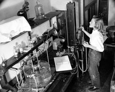 a woman standing in a room filled with lots of bottles and equipment on top of shelves