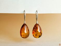 "Natural Baltic amber cognac color earrings is a perfect choice for classy style admirers! Perfect choice to brighten up office outfit or look even more beautiful on a special occasion! Shaped in drop form these earrings look delicate yet fancy. MATERIALS AND SIZE: Stone: 100% Natural Baltic Amber Findings: sterling silver 925 Earrings A: Weight: 6 g (0,21 oz) Bead size: 2,8 cm (1,1 in) x 1,4 cm (0,55 in) Total earring length: 4.9 cm (1,92in) Earrings B: Weight: 5,49 g (0,20 oz) Bead size: 2,3 c Elegant Brown Earrings For Party, Elegant Brown Dangle Earrings, Classic Amber Earrings For Gift, Handmade Dangle Teardrop Earrings For Formal Occasions, Handmade Orange Earrings For Formal Occasions, Handmade Teardrop Earrings For Formal Occasions, Handmade Teardrop Dangle Earrings For Formal Occasions, Classic Orange Earrings For Formal Occasions, Handmade Formal Teardrop Dangle Earrings