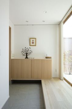 an empty room with a large wooden cabinet and plant on the top shelf in front of a sliding glass door