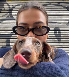 a woman wearing glasses holding a dog in her arms and looking up at the camera