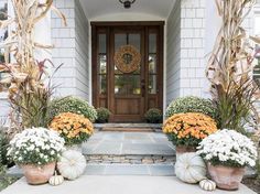 two large pumpkins are sitting in front of a door with flowers on the steps