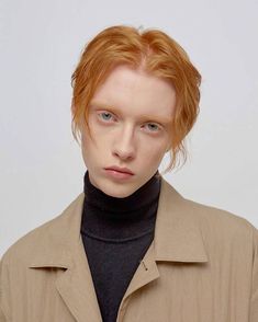 a man with red hair wearing a tan coat